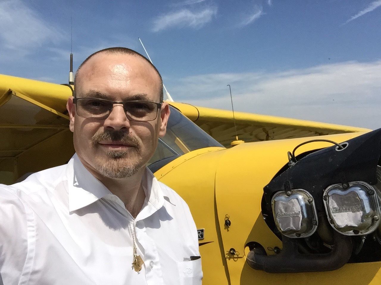 Nicolas devant un avion ancien jaune et des lunettes de vol historiques